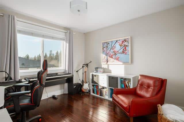 Home office with a view in Vancouver, featuring a desk, ergonomic chair, Guitar, white bookshelf, and modern decor for a comfortable workspace.