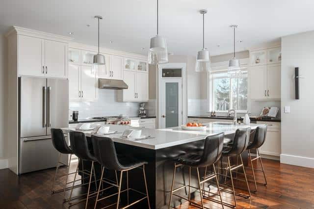Modern kitchen with white cabinetry and stainless steel appliances, perfect for family meals and entertaining. Featuring a spacious island and stylish pendant lighting.
