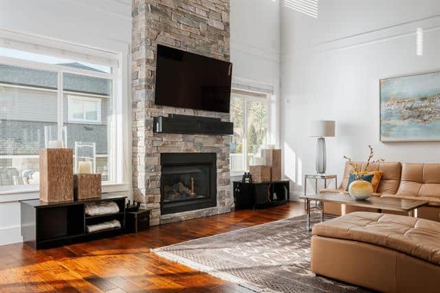 Modern living room with stone fireplace and large windows, showcasing luxury home interior in Victoria, BC; perfect for buyers searching for upscale real estate in the area.