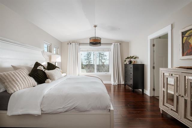 Comfortable master bedroom with large window, modern decor, and hardwood flooring, ideal for homebuyers in Victoria, BC. Listing by Orca Realty Inc.