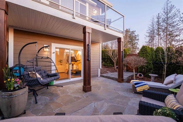 Spacious backyard patio with outdoor seating, lush greenery, and modern deck area, ideal for outdoor living and entertaining in Vancouver’s real estate market.