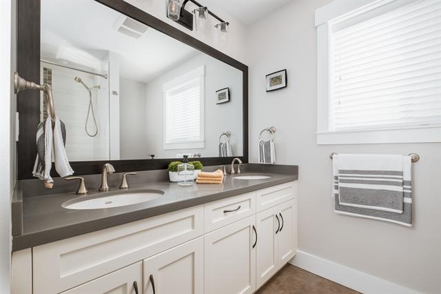 Bright modern bathroom vanity with double sinks, large mirror, and natural light, showcasing contemporary home interior design.