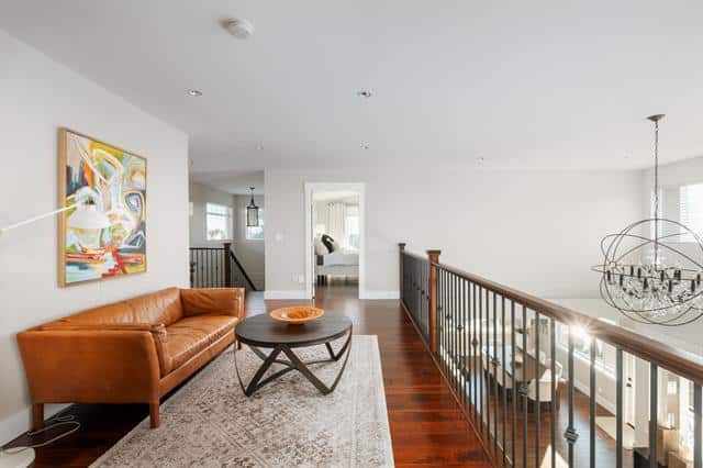 Bright modern living room with white walls, hardwood floors, leather sofa, and contemporary decor, showcasing upscale home interiors.