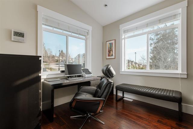 Modern home office space with large windows, black leather chair, and minimalist decor, perfect for real estate professionals or remote work environments.