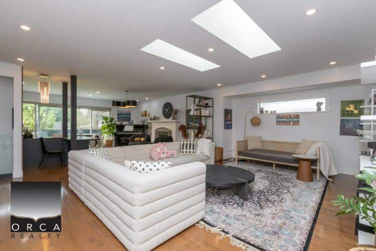 Bright modern living room with stylish furniture, large windows, and natural light, showcasing contemporary design and cozy ambiance at Orca Realty Inc.