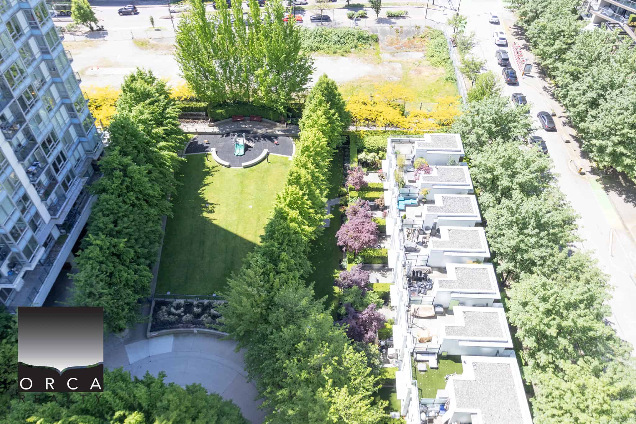 Lush green park with playground on top of condo rooftops, surrounded by trees and urban landscape, showcasing modern Vancouver real estate and outdoor amenities.