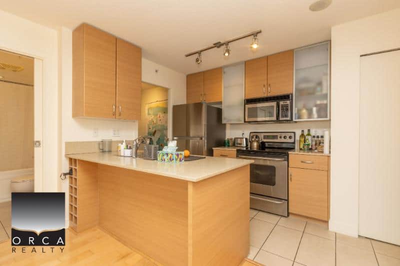 Modern suburban kitchen with stainless steel appliances and wooden cabinetry, ideal for Vancouver-area homes listed by Orca Realty Inc.