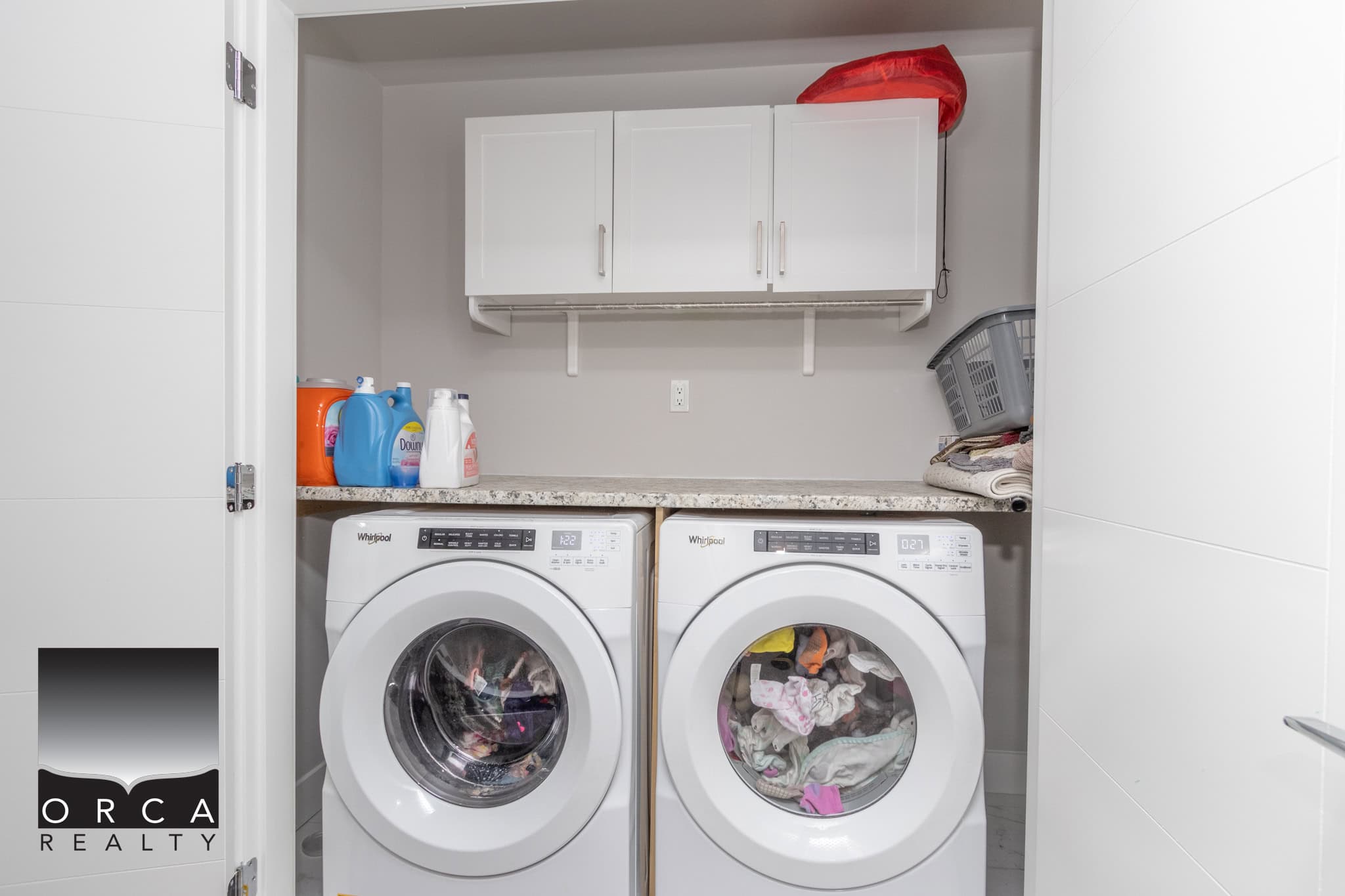 9 Bright laundry room with modern washer and dryer, ample storage cabinets, and laundry supplies, showcasing a clean and organized space perfect for property listings by Orca Realty Inc.
