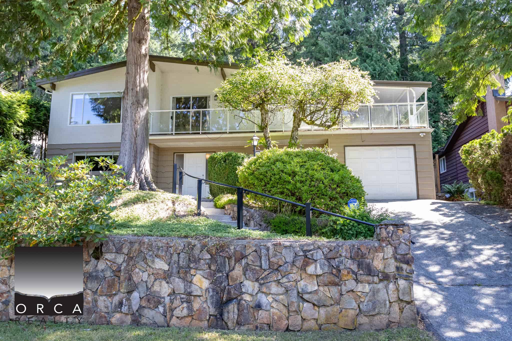 Charming residential home with a lush garden and mature trees, featuring an inviting driveway, balcony, and modern design elements, perfect for real estate listings under Orca Realty Inc.