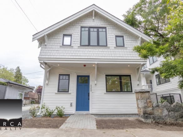Modern white two-story house with black window frames and a vibrant blue front door, located in a friendly neighbourhood in Vancouver, offering charming curb appeal and great potential for families.