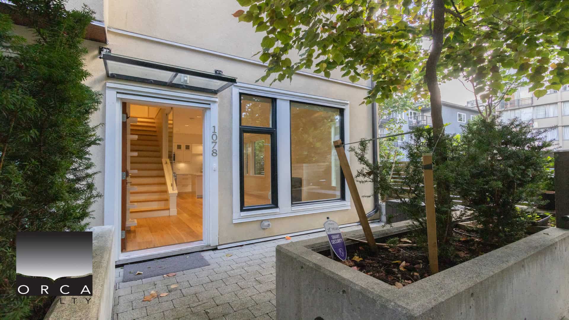 Modern Vancouver Westtown house entrance with large windows, wooden staircase, and landscaped front yard, showcasing Orca Realty's innovative real estate listings in BC.