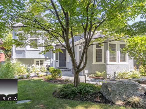 Lush front yard with mature tree and landscaped garden surrounding a charming modern house, showcasing Orca Realty Inc. services for Vancouver Island real estate buyers and sellers.