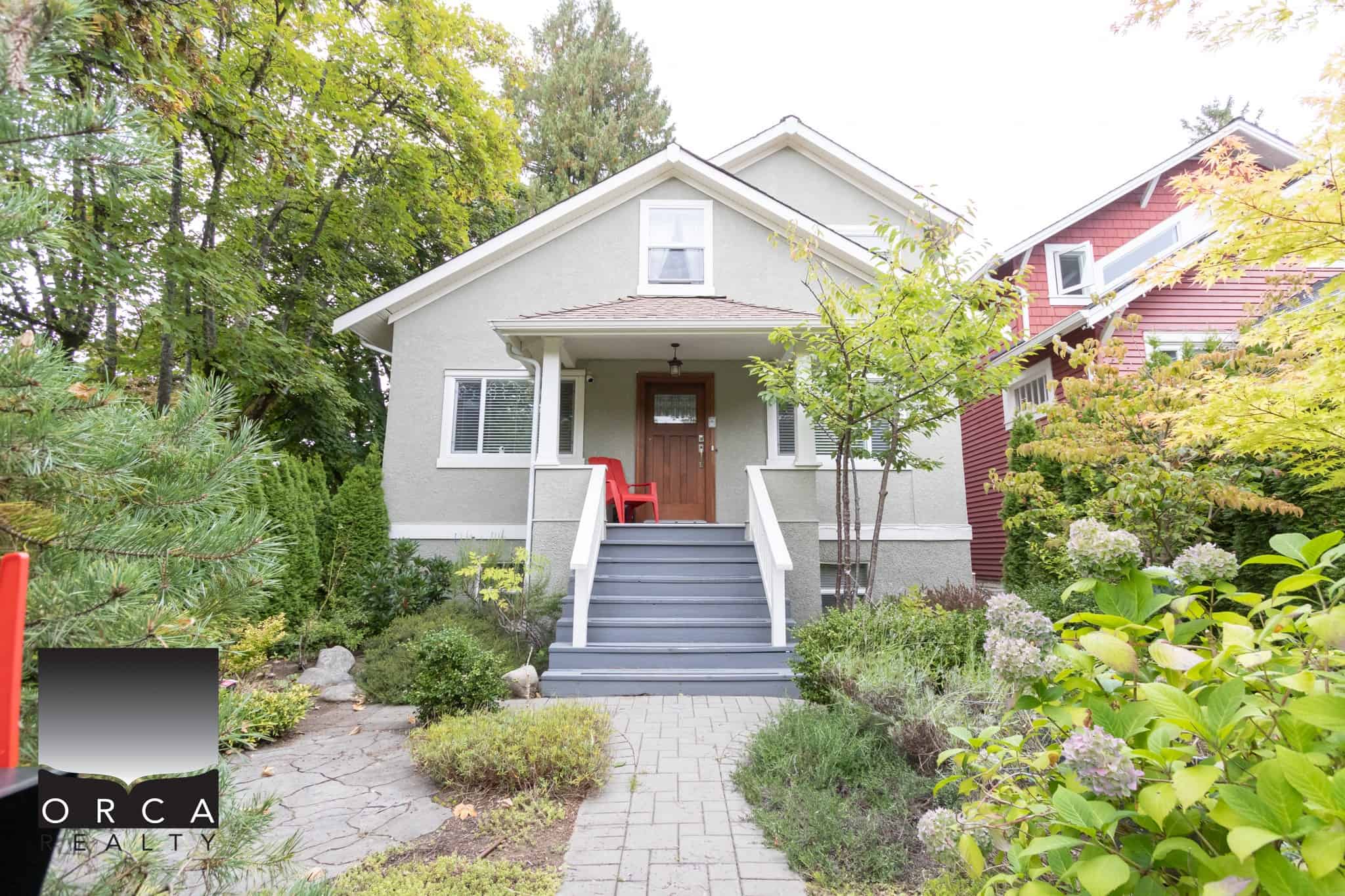 Charming Vancouver home exterior with lush landscaping, colorful garden, and inviting front steps, showcasing Orca Realty's premium real estate services in British Columbia.