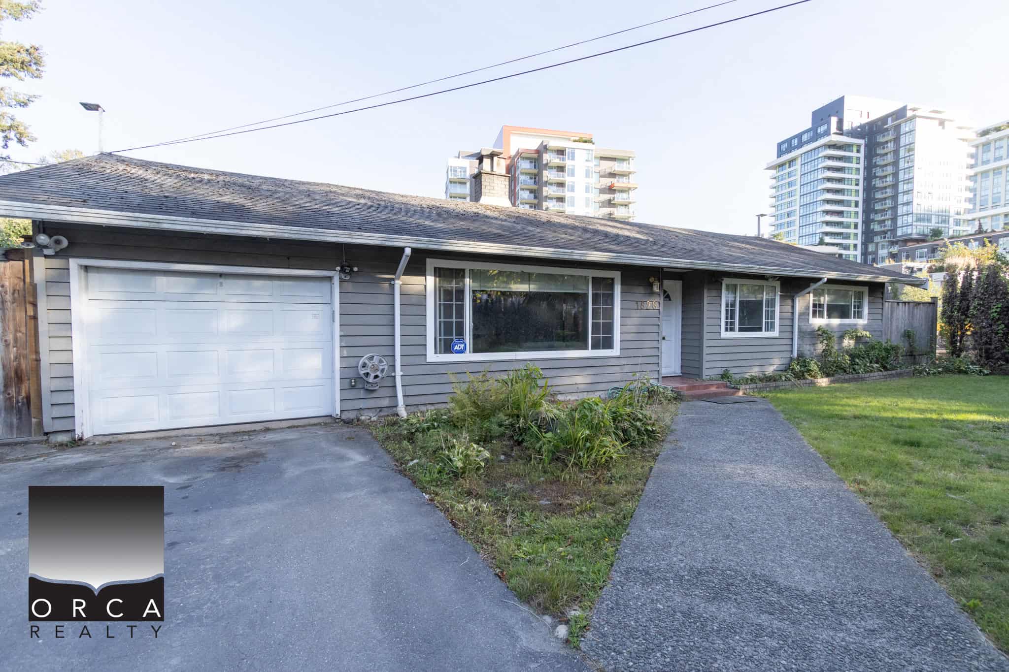 01 Cozy grey single-story house with attached garage, front lawn, and urban surroundings, ideal for Vancouver real estate buyers looking for a charming home with modern amenities.