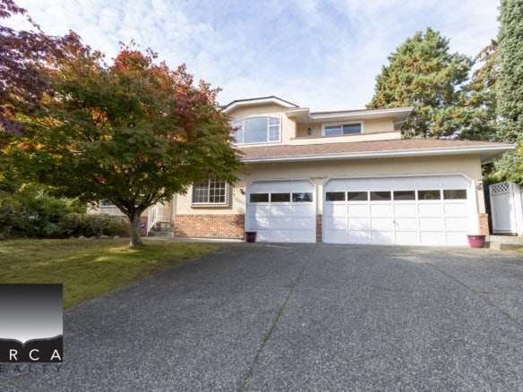 Spacious two-car garage home with landscaped front yard, mature trees, and classic architecture, showcasing a valuable property listing for Orca Realty Inc. in BC.