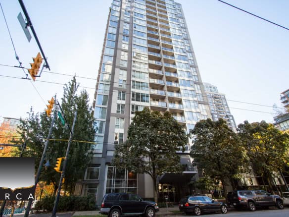 Modern high-rise condo building in Vancouver's urban core, featuring expansive glass windows and balconies, prime real estate for luxury city living and investment opportunities.