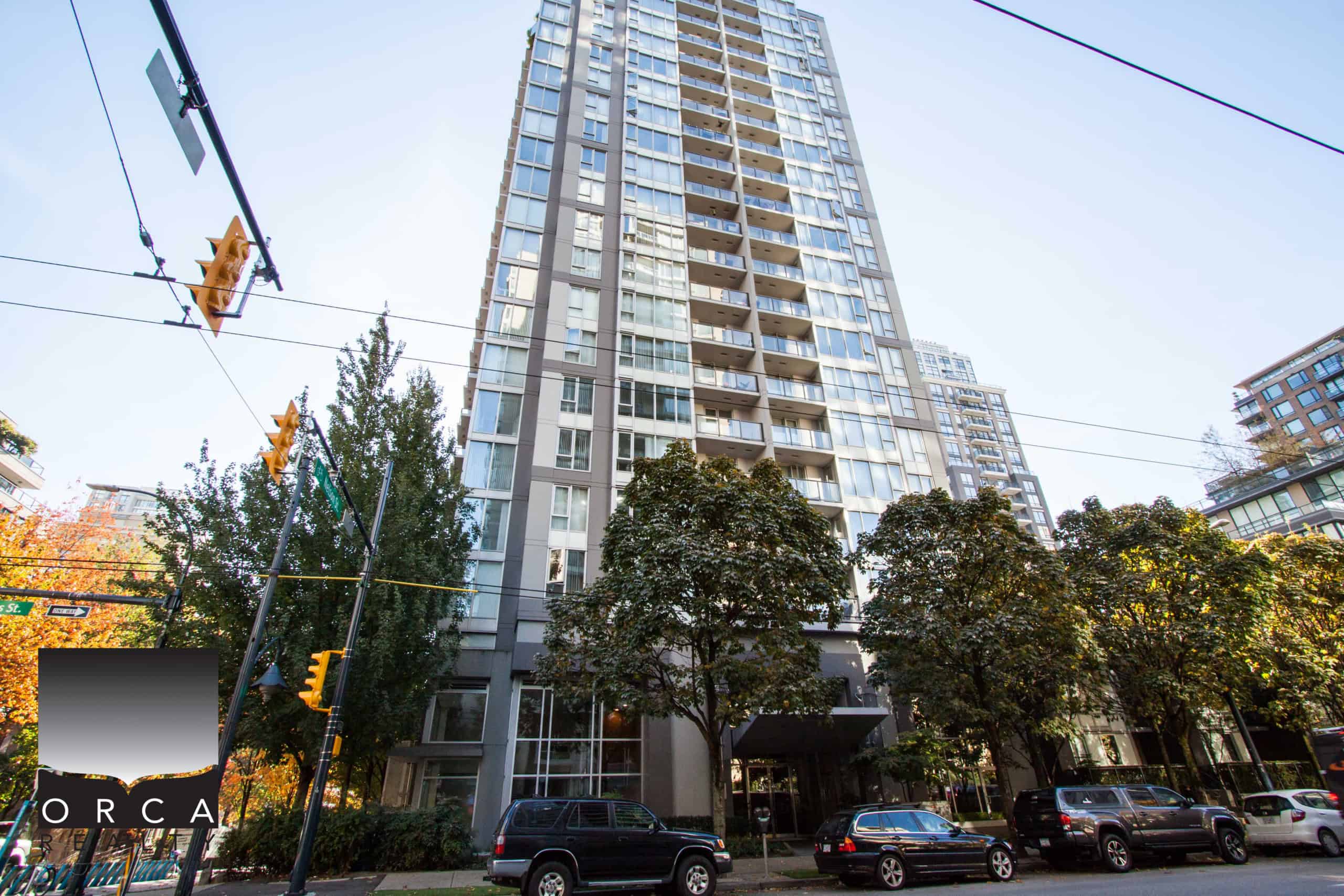 Modern high-rise condo building in Vancouver's urban core, featuring expansive glass windows and balconies, prime real estate for luxury city living and investment opportunities.