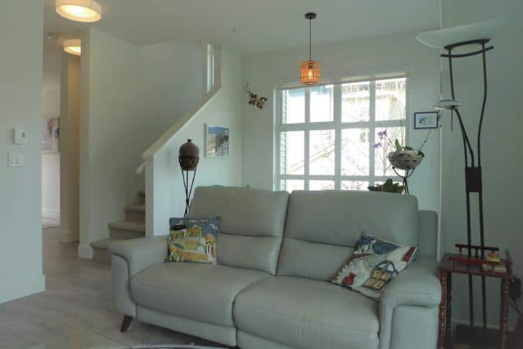Cozy modern living room with natural light and stylish decor in a Toronto home, featuring a white sofa, decorative pillows, and contemporary lighting, ideal for real estate listing photos.