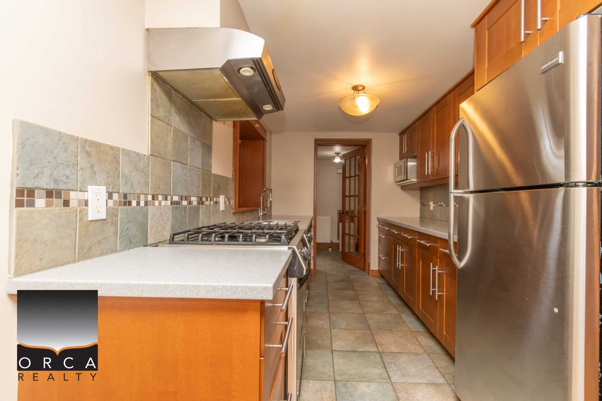 Modern kitchen with stainless steel appliances, wooden cabinetry, tile backsplash, and ample counter space for home cooking in Vancouver, BC.