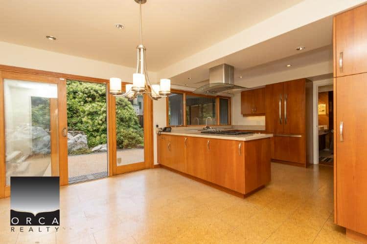 Bright modern kitchen with wooden cabinets, stainless steel appliances, and large sliding glass doors leading to a garden. Perfect for family living and entertaining.