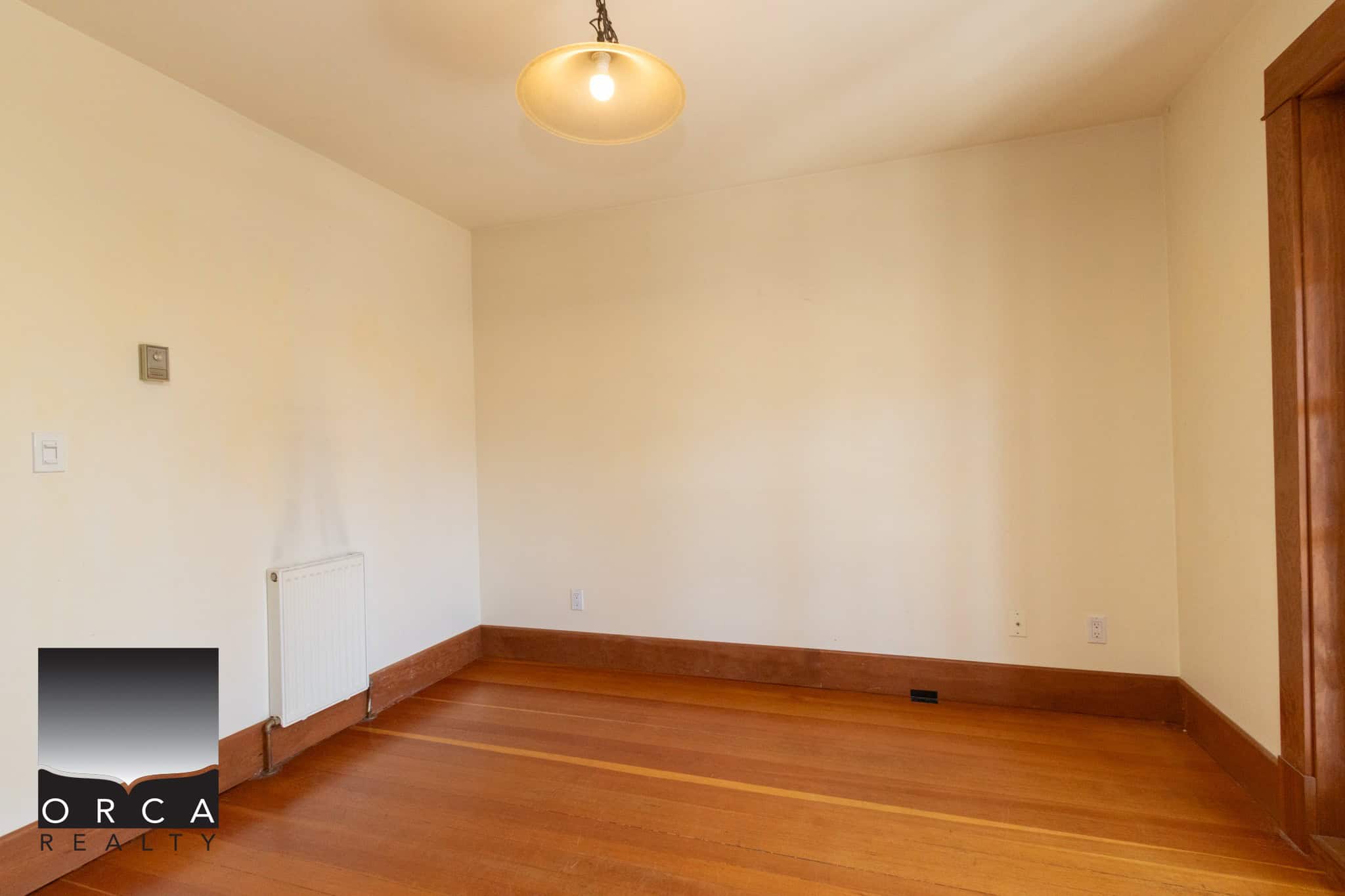 Bright empty room with hardwood floors, cream walls, and natural wood trim, ideal for residential or office space, showcasing quality craftsmanship and a neutral aesthetic for versatile decorating options.