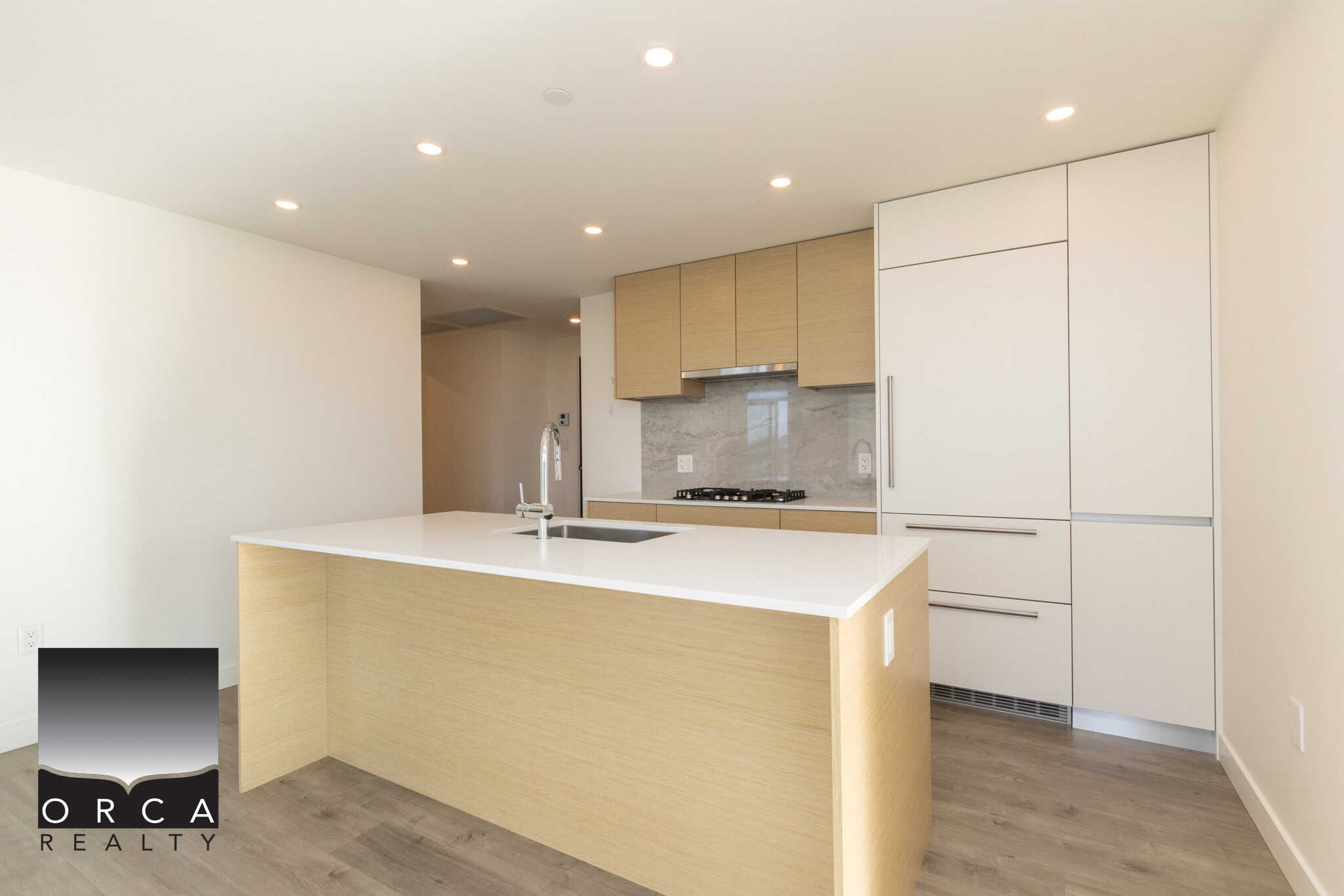 Modern minimalist kitchen with light wood and white cabinetry, quartz island, and stainless steel appliances, perfect for Vancouver-area homes.