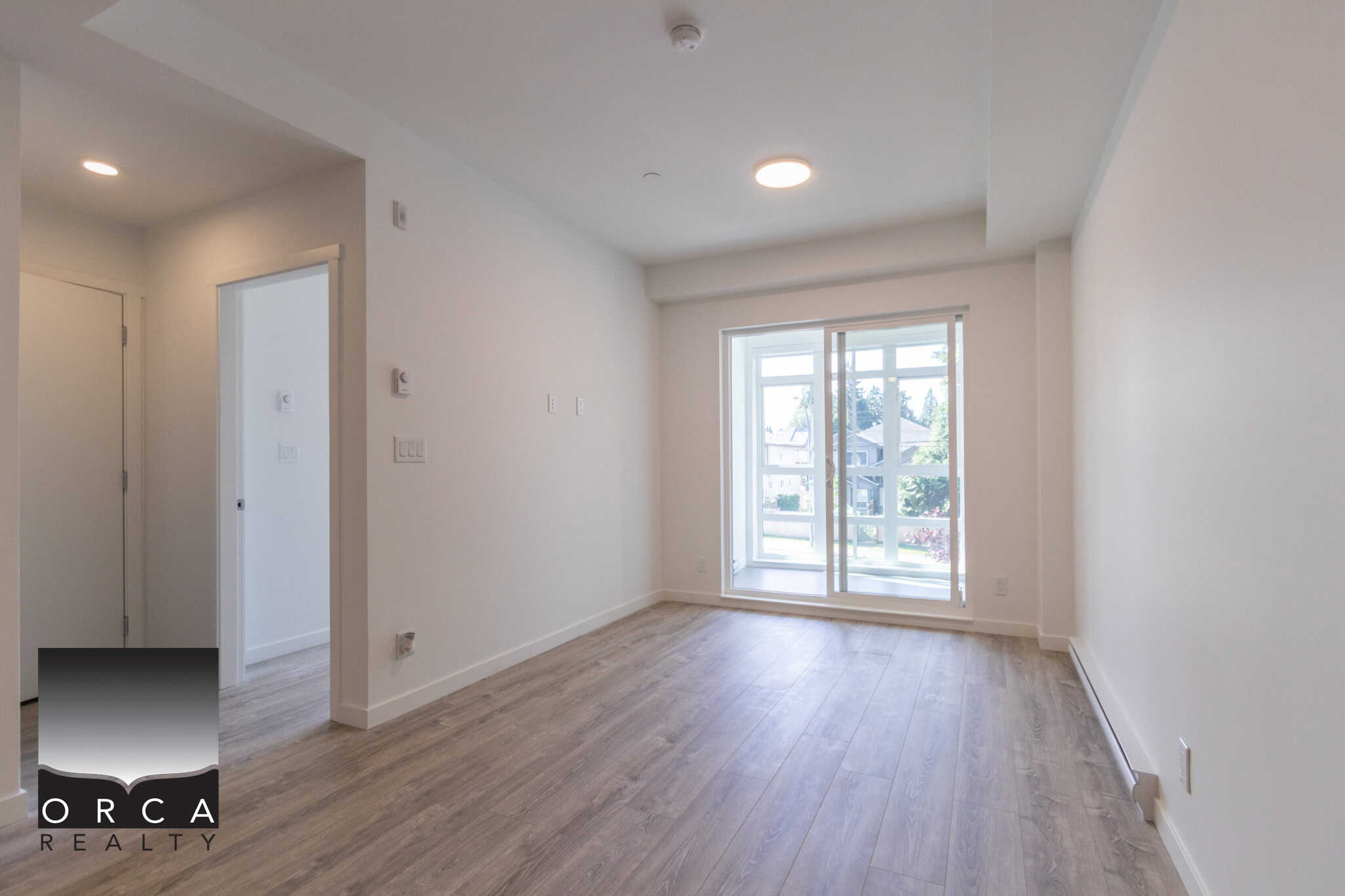 Bright open living room with large glass sliding doors, natural light, modern flooring, perfect for Vancouver Island real estate buyers.