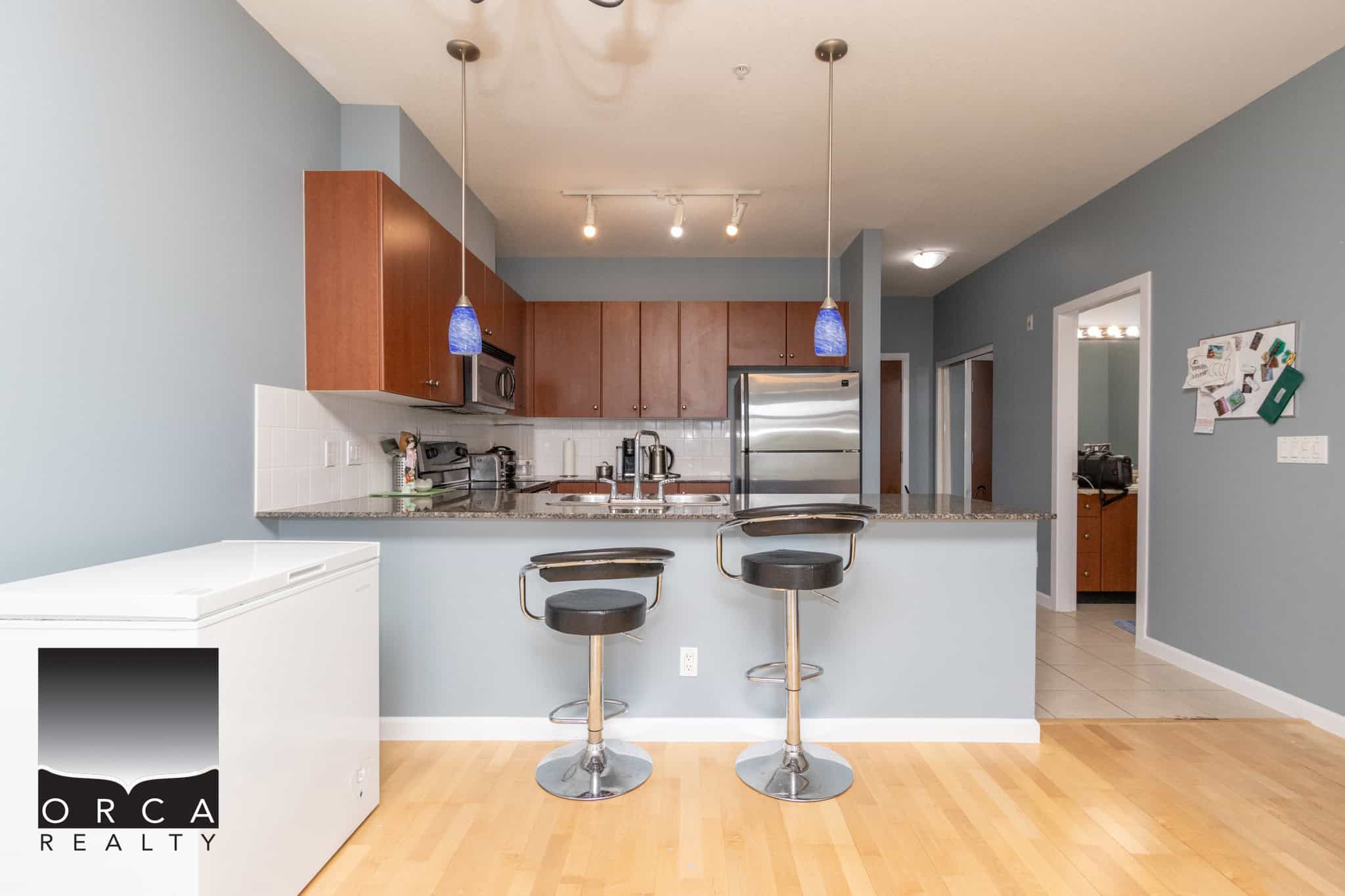 Modern Vancouver-style kitchen with granite countertops, wooden cabinets, stainless steel appliances, and a breakfast bar, perfect for family living and entertaining.