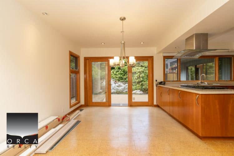 Bright open-concept kitchen and dining area with large windows and sliding glass doors, ideal for family living and entertaining, featuring modern appliances and warm wooden accents.
