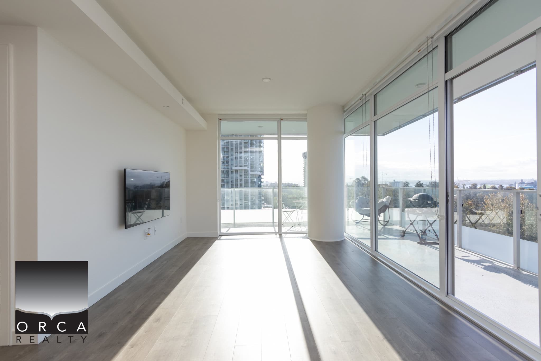 Modern high-rise apartment living with floor-to-ceiling windows and spacious balcony, offering stunning city and water views in Vancouver’s vibrant real estate market.