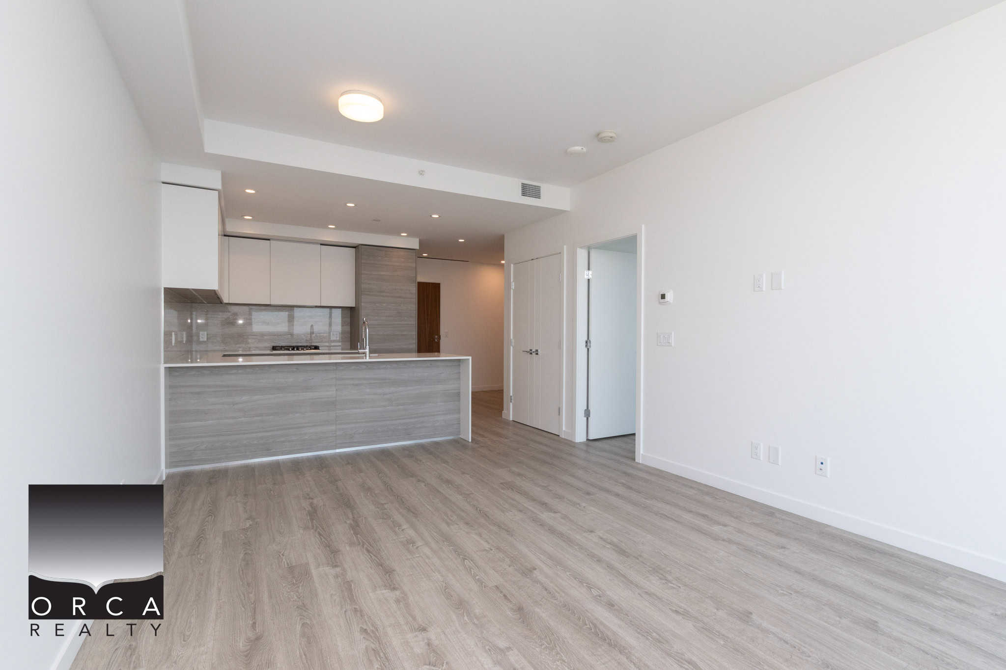 11 Spacious modern open-concept living area with kitchen in a new Vancouver condominium, featuring sleek cabinetry and light wood flooring. Ideal for contemporary urban living in BC.