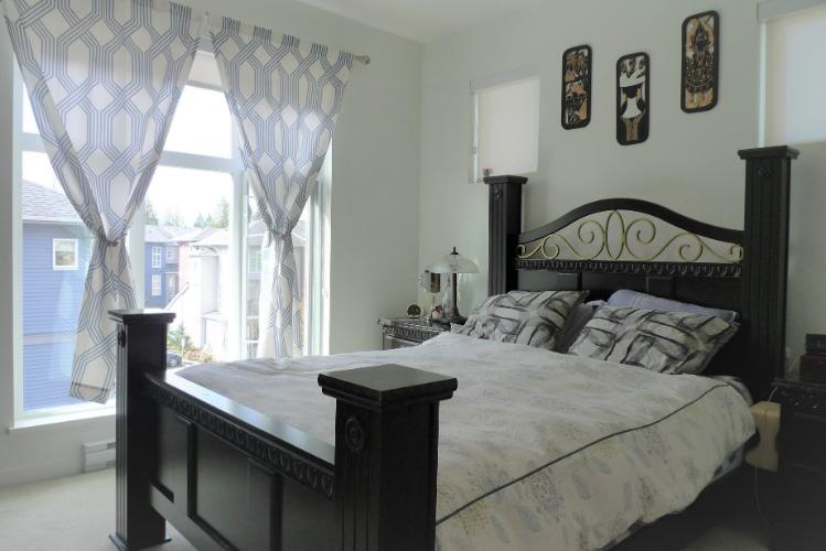 Bright bedroom with large windows, stylish curtains, and a black wooden bed frame; ideal for homebuyers and real estate listings in Vancouver and BC.