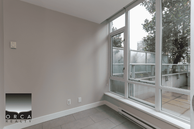 Bright modern apartment with large floor-to-ceiling windows showcasing urban views, ideal for Vancouver real estate buyers looking for contemporary condo living.