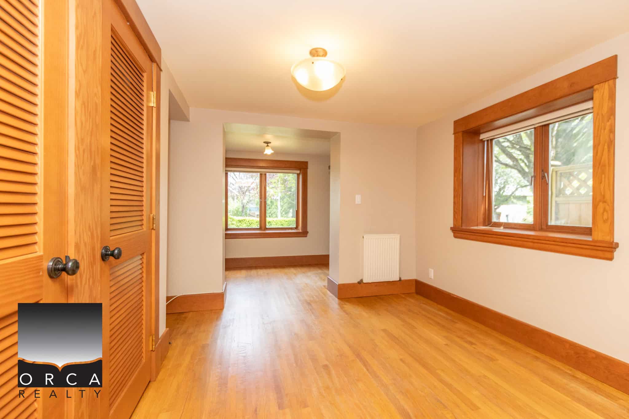 Bright living room with large windows and hardwood floors, showcasing a cozy and inviting home interior ideal for families and homebuyers in Ottawa, Ontariothat values natural light and warm wood accents.