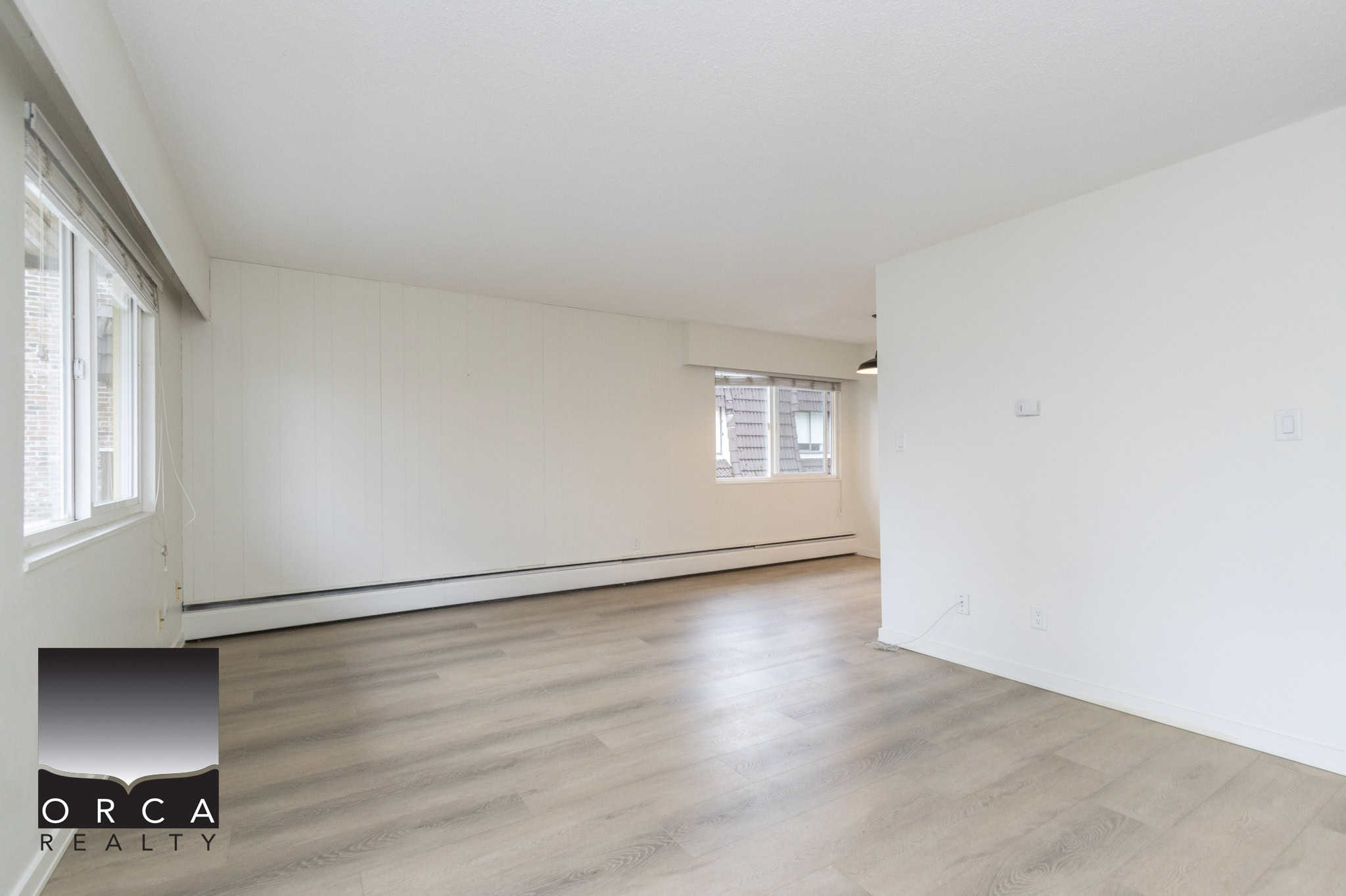 Spacious open-concept living room with natural light, white walls, and light wood flooring, perfect for Vancouver real estate buyers seeking modern condos or apartments.