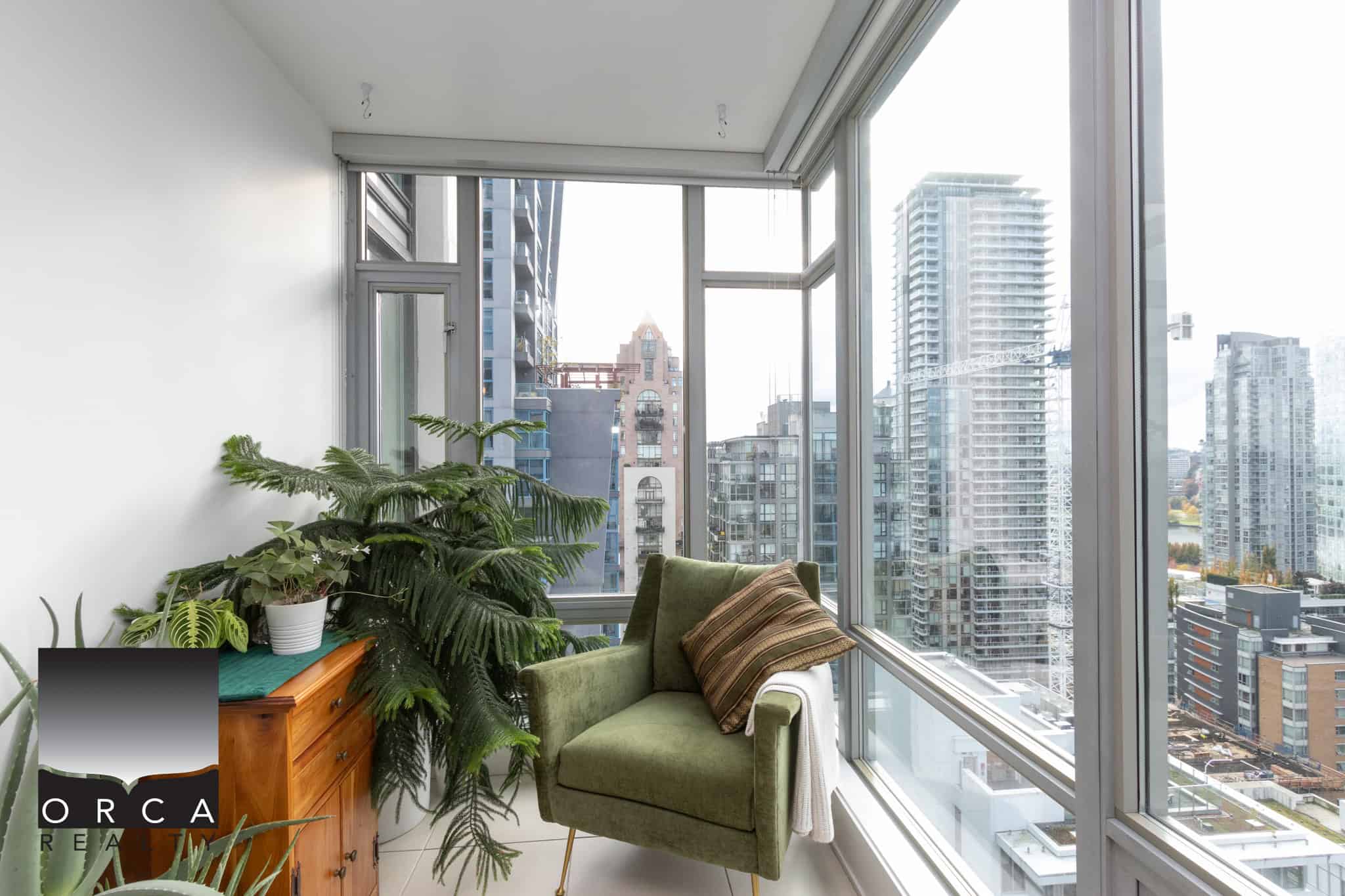 Bright modern condo interior with large windows showcasing city skyline views in Vancouver. Luxurious urban living space with stylish furniture, indoor plants, and natural light.