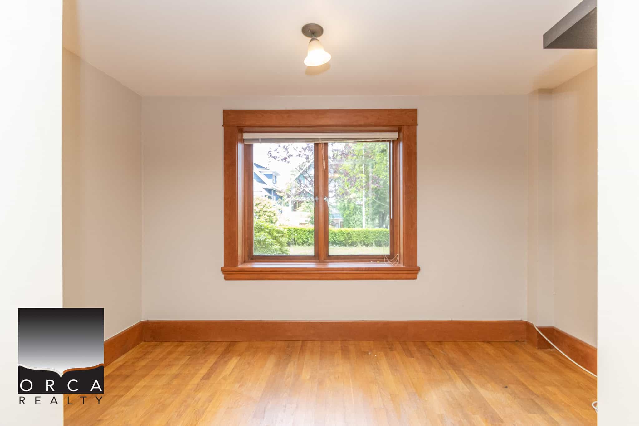 Bright empty room with large window, hardwood floors, and natural light, ideal for home staging or real estate listings in Vancouver. Focuses on cozy, inviting interior spaces.