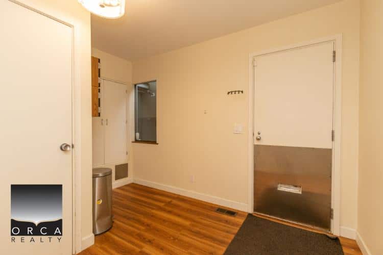 Bright interior entryway with hardwood flooring, white walls, and a metallic front door, perfect for Vancouver area homes.