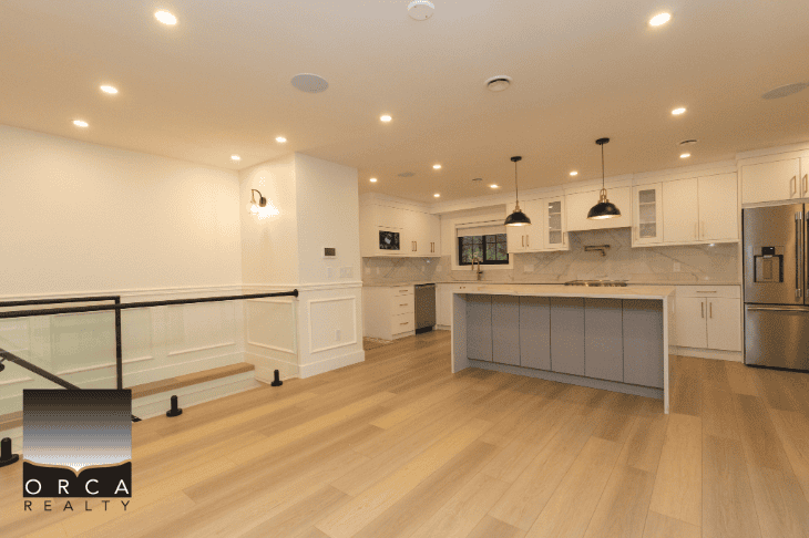 Modern open-concept kitchen with white cabinetry, stainless steel appliances, and a central island featuring pendant lighting, perfect for Vancouver real estate buyers.