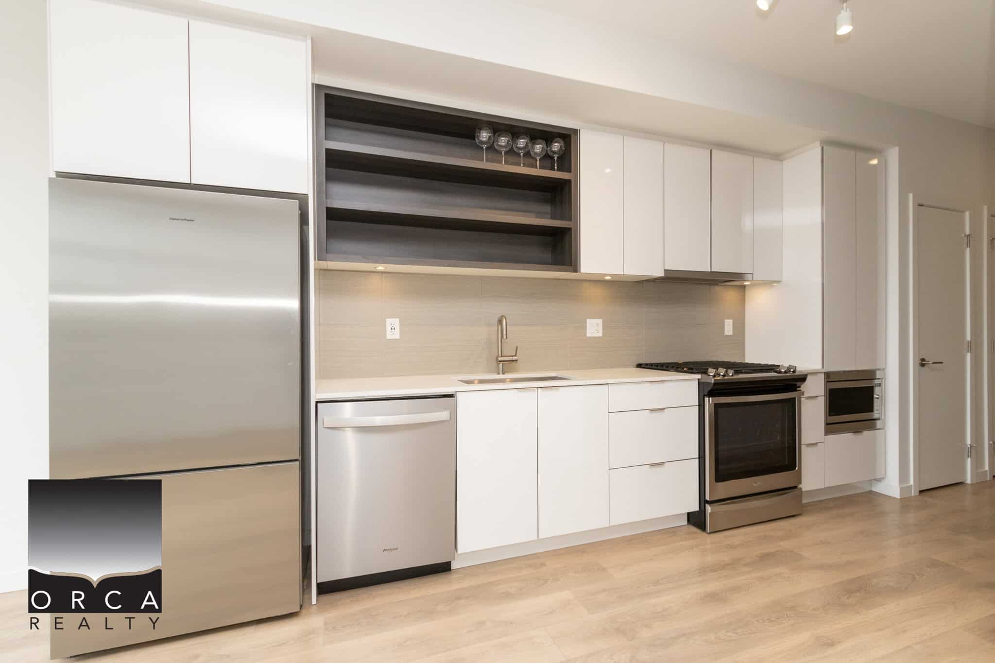 Modern stainless steel refrigerator and sleek white kitchen cabinetry in a contemporary Vancouver home for sale.