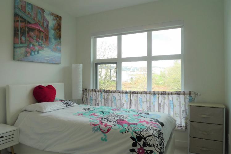 Bright bedroom with large window, colorful floral bedding, and modern decor in Vancouver home for sale by Orca Realty Inc. Spacious and inviting interior perfect for home buyers.