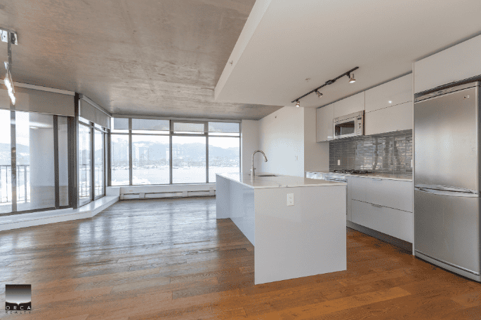 Large modern open-concept kitchen and living space with floor-to-ceiling windows, waterfront views, high-end appliances, ideal for Vancouver real estate buyers.