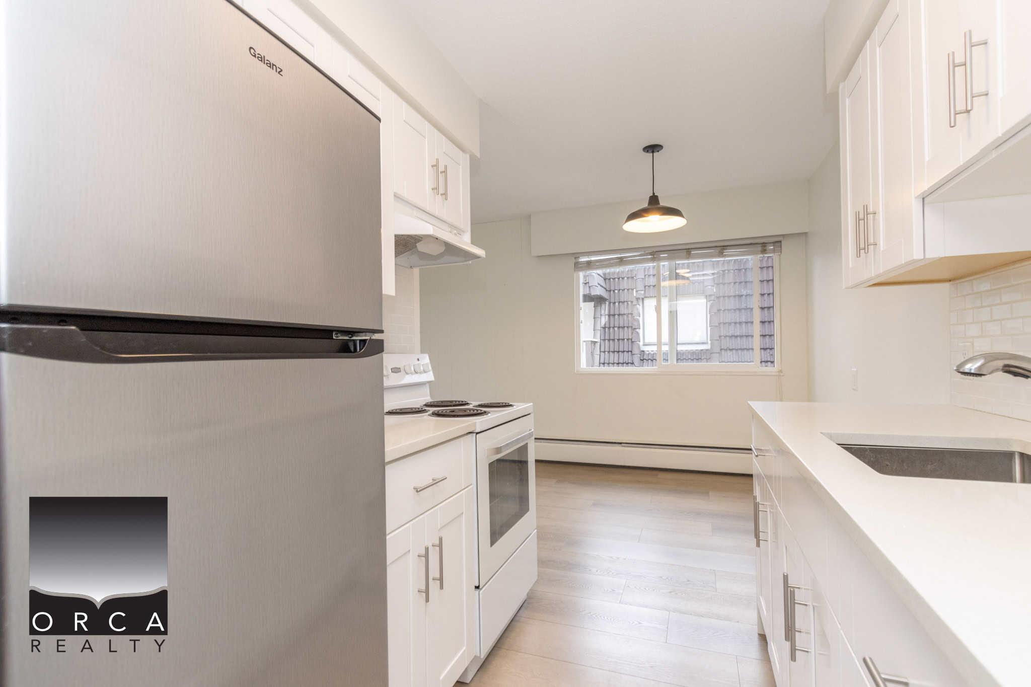 Stainless steel refrigerator and white kitchen cabinets in a modern condo unit, showcasing a bright and clean kitchen space ideal for Vancouver real estate listings and property sales.