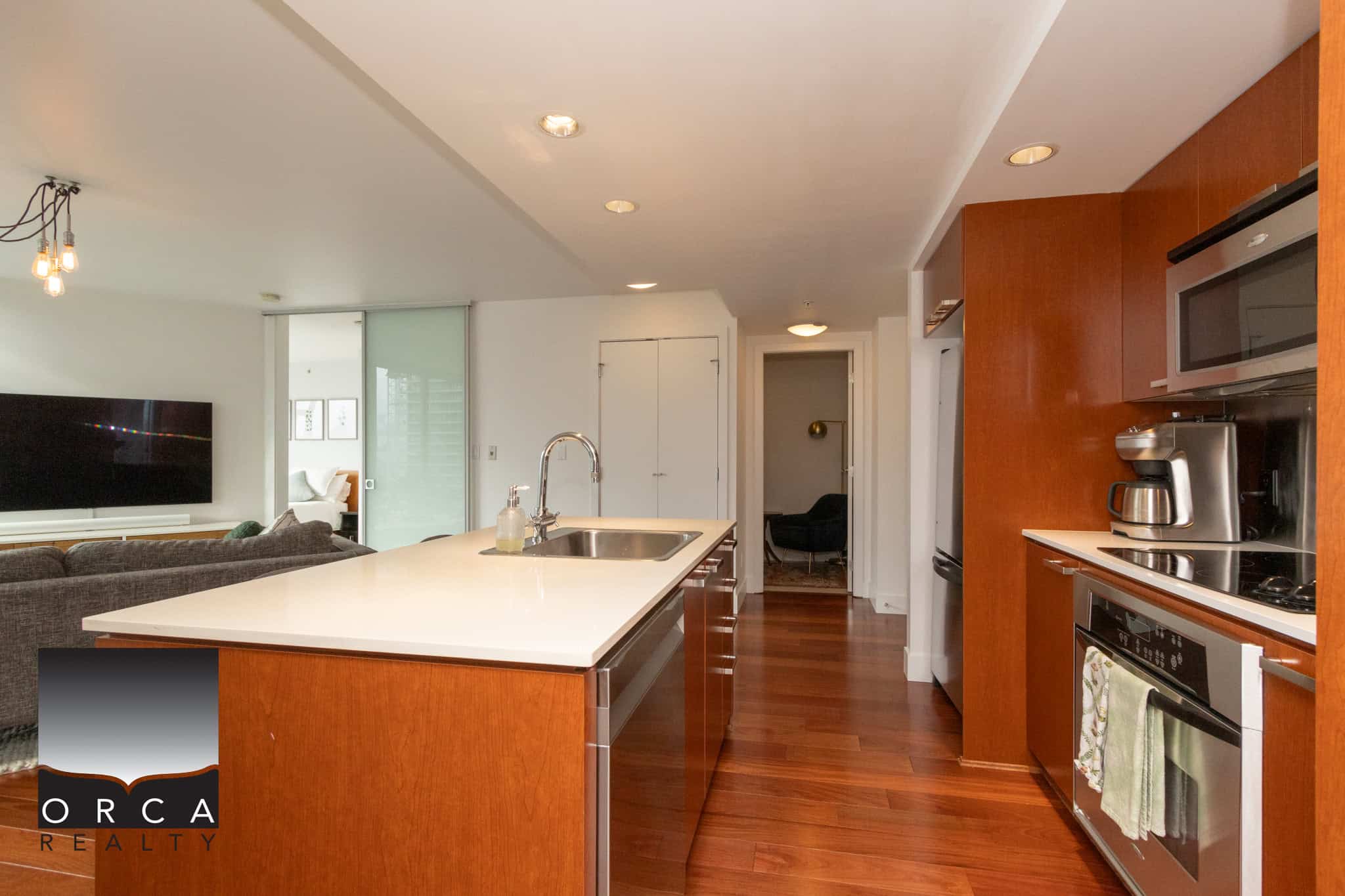 Bright modern kitchen with stainless steel appliances, hardwood floors, and open-concept living space in Vancouver, BC, perfect for contemporary urban living.