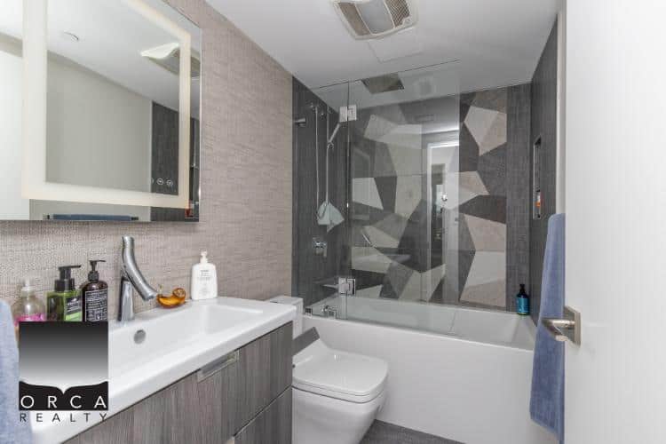 Modern bathroom in a contemporary condo, featuring a sleek vanity, stylish shower with geometric tile design, and modern fixtures, perfect for Vancouver real estate buyers.