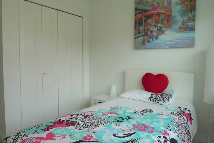 Cozy bedroom with colorful bedding, a heart-shaped pillow, and artistic wall decor, ideal for real estate listings and home staging to attract buyers.