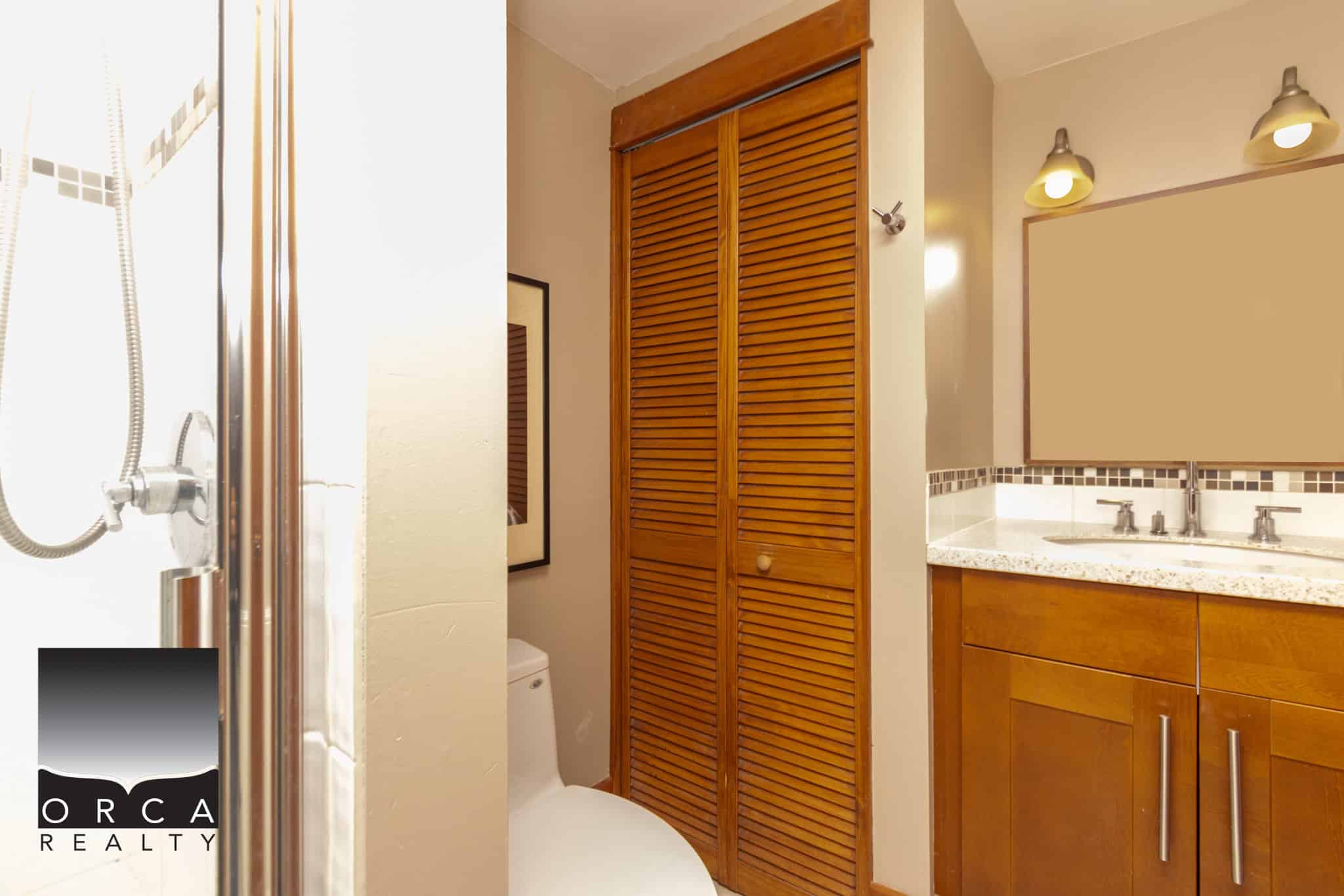 Bright bathroom with wooden accents, walk-in shower, and granite countertop featuring dual sinks in a modern, cozy home interior. Perfect for prospective clients seeking Vancouver Island properties.