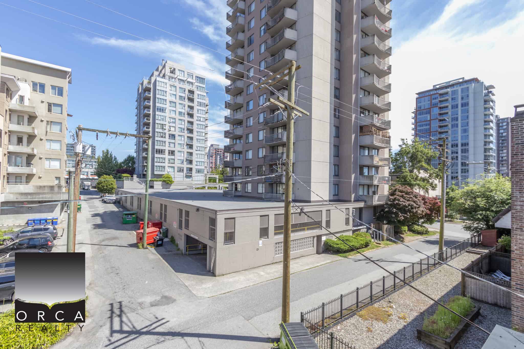 Modern high-rise residential buildings in Vancouver, BC with surrounding greenery and parking, exemplifying urban living spaces offered by Orca Realty Inc. in a vibrant city setting.