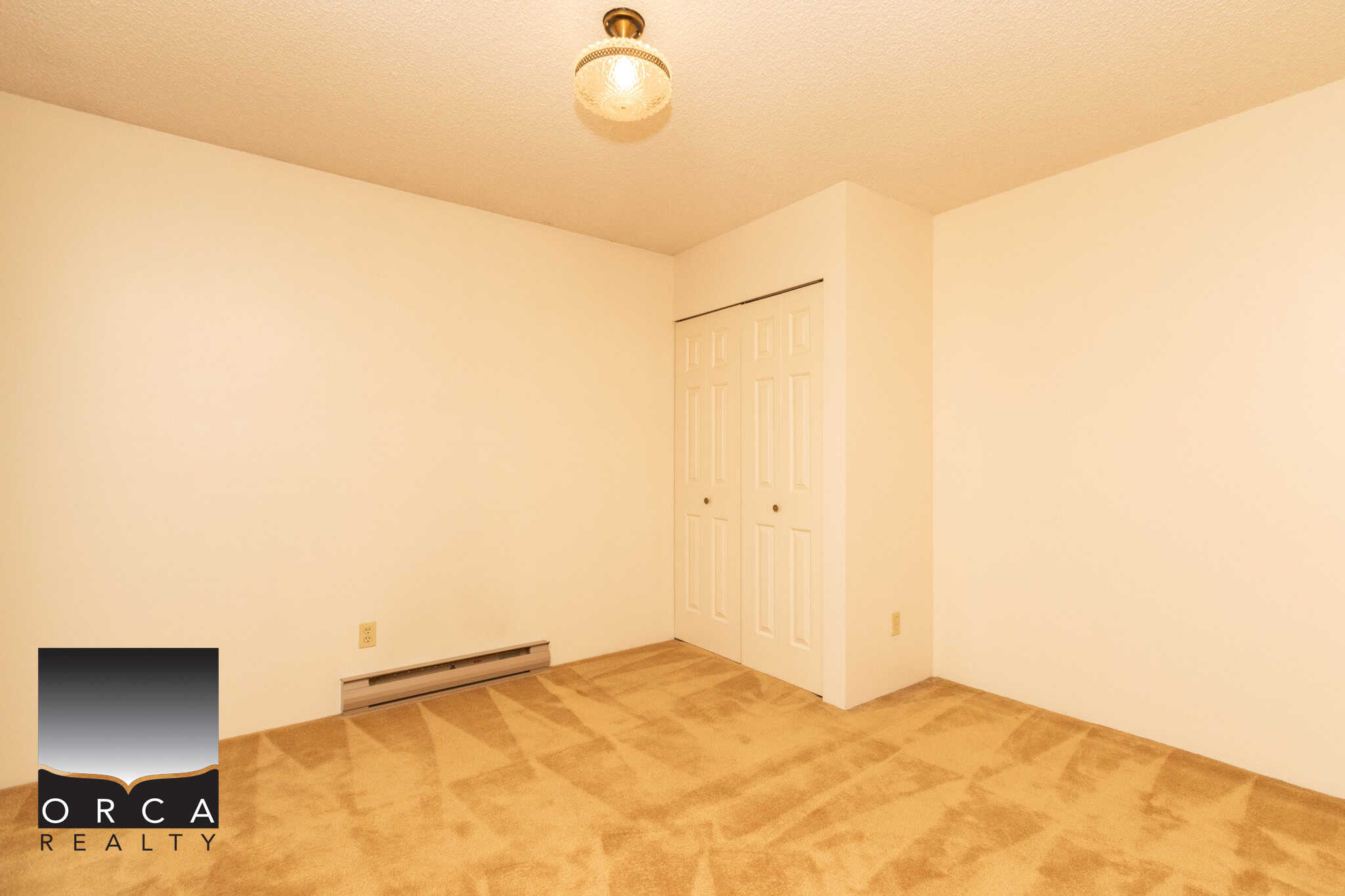 Bright empty bedroom with beige carpet, white walls, double closet doors, and a ceiling light fixture, showcasing a spacious and clean interior ideal for potential home buyers.