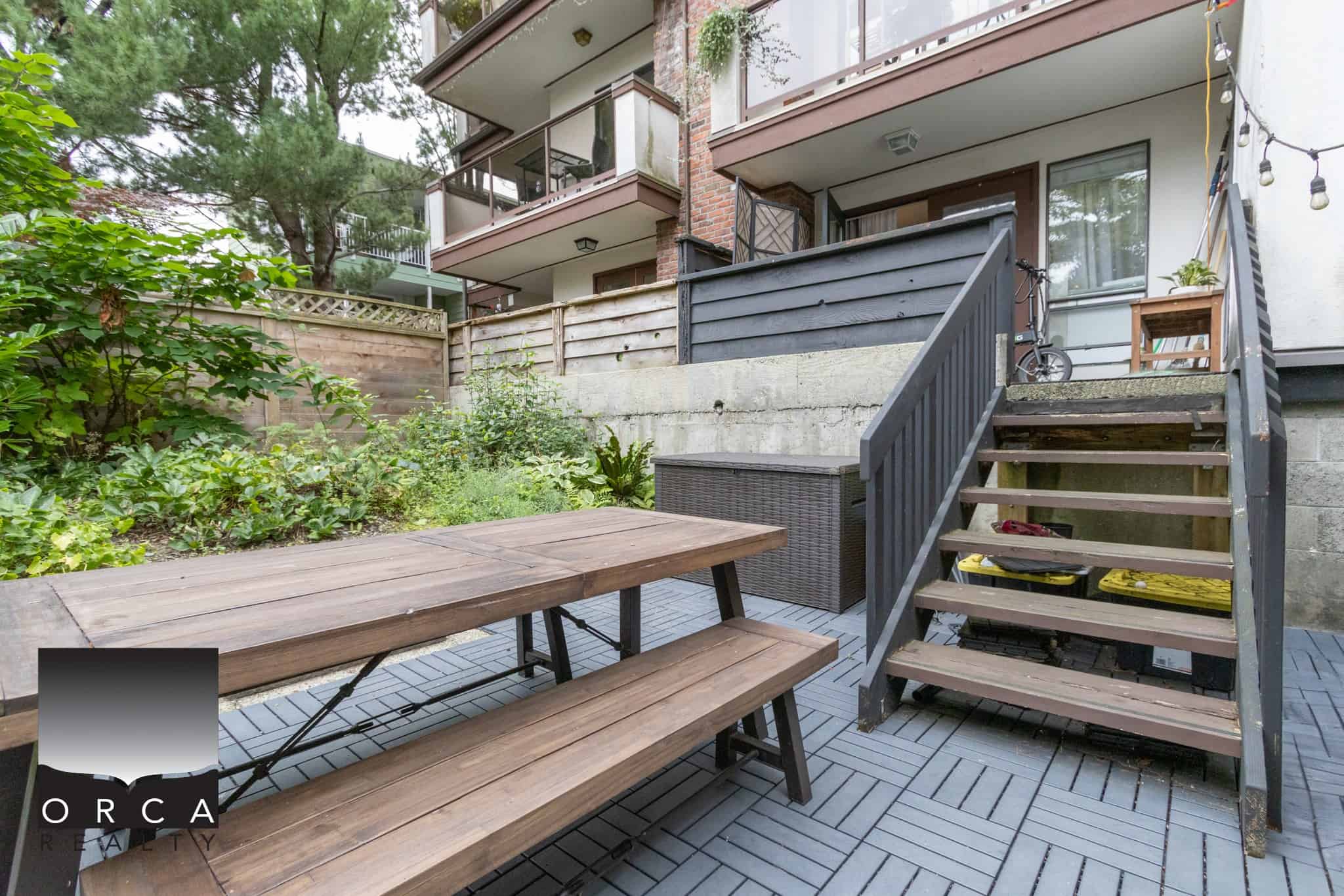 Cozy backyard patio with wooden dining table and surrounding greenery, ideal for relaxation and outdoor dining in Vancouver’s real estate market.